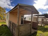 une petite cabane en bois avec un porche couvert, au milieu de l'herbe