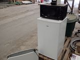 a microwave sitting on top of a refrigerator in a warehouse