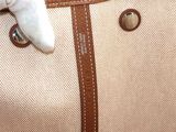 someone ' s hand holding a beige and brown bag with a white glove on top of it