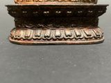 a small metal bowl with a gold decoration on it