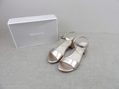 sandales en cuir argenté avec bride à la cheville et bout ouvert, présentées devant une boîte blanche