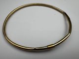a close up of a gold bracelet on a white surface