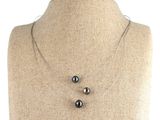 trois perles noires suspendues à une chaîne en argent autour du cou d'un mannequin