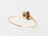a gold ring with a red stone and two white diamonds
