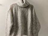Le pull est suspendu à un cintre accroché au mur.