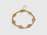 gros plan d'un bracelet en or sur fond blanc