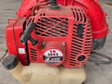 a close up of a red and black blower sitting on top of a cement floor