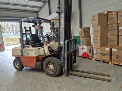 un chariot élévateur dans un entrepôt, avec des cartons au sol