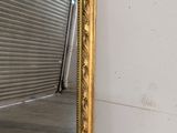 a large gold mirror sitting on the floor in front of a wall