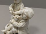 a small figurine of a boy and a boy sitting on a stool