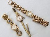 three watches and a bracelet are sitting on a white surface