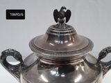 a silver teapot with a bird on top of it