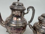 two silver teapots sitting next to each other on a table