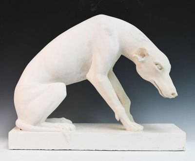 une sculpture blanche représentant un chien assis sur un socle blanc