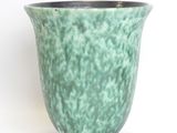 a green vase that is sitting on a white surface