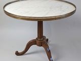 une table au plateau en marbre blanc, avec un piètement en bois, sur fond gris