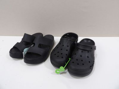 une paire de sandales Crocs noires posées sur une surface blanche