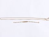 a gold necklace and a gold bracelet on a white background