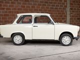 a small white car that is parked in front of a brick wall