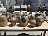 many vases sitting on a table in a yard