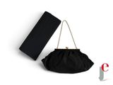 La pochette noire se trouve à côté d'un sac à main noir