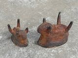 two old rusted metal animal heads on a cement surface