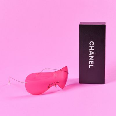 Lunettes de soleil roses Chanel et leur étui sur fond rose
