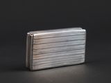 a silver cigarette case sitting on top of a black table