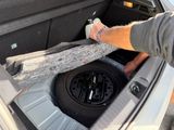 a man opening the trunk of a car with his foot in it