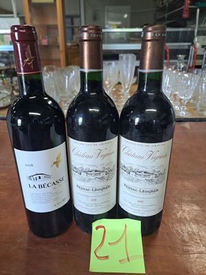 Trois bouteilles de vin sont posées sur une table, accompagnées d'une étiquette de prix