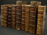 Plusieurs vieux livres sont alignés sur fond noir
