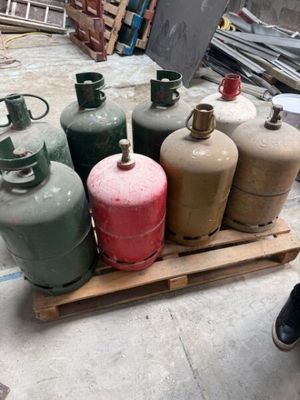 Plusieurs bouteilles de gaz propane sont empilées sur une palette dans un entrepôt