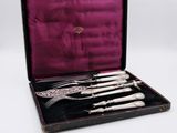 un service d'argenterie ancienne présenté dans un coffret noir doublé de velours violet