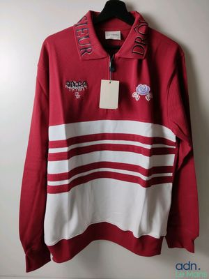 a red and white sweater hanging on a hanger on a wall