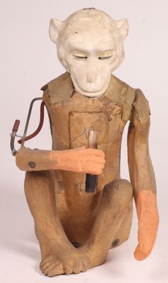 une sculpture en bois représentant un singe tenant un marteau à la main