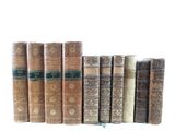several old books are lined up in a row on a white surface