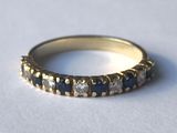 une image d'une bague en or avec des pierres bleues et blanches