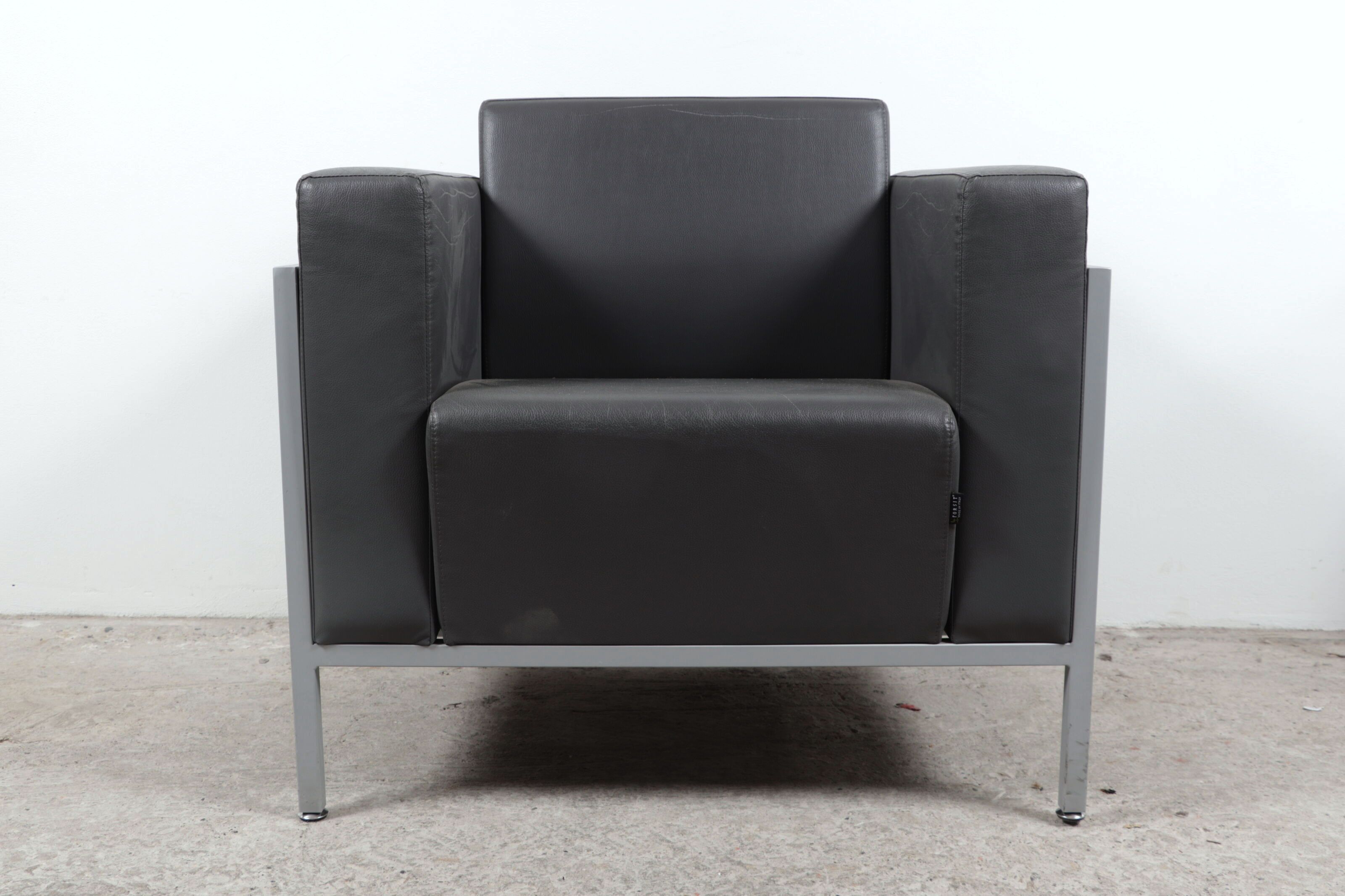 FORSIT. Fauteuil moderniste recouvert de similicuir gris. H_84 cm L_69 cm P_86 cm, état d'usage, griffures aux accotoirs