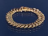 un gros plan d'un bracelet en or sur un fond bleu