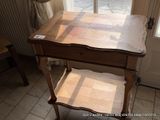 a wooden table with a drawer on it in front of a window