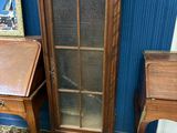 une armoire en bois avec une porte vitrée, à côté d'une petite table
