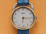 une image représentant une montre-bracelet avec un bracelet bleu sur un fond jaune