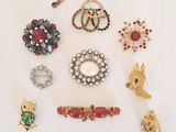 several different brooches and pins are arranged on a white surface