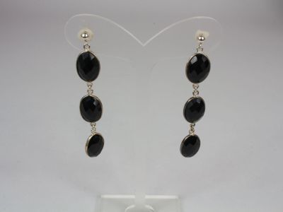 a pair of earrings with black stones hanging from them