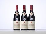 three bottles of red wine sitting on top of a table