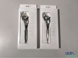 two pairs of scissors are in a box on a table