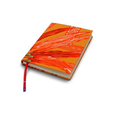 un cahier orange sur lequel repose un crayon, posé sur une surface blanche