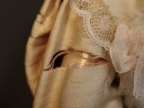a close up of a doll wearing a dress and bonnet