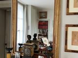 un miroir posé sur une table dans une pièce où sont accrochés des tableaux aux murs