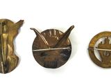 three antique brass brooches of various shapes and sizes on a white surface